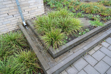 Aus den Regenrohren fließt das Dachwasser in offene Rinnen. Sichtbar wird es in Schöpfbecken geleitet.